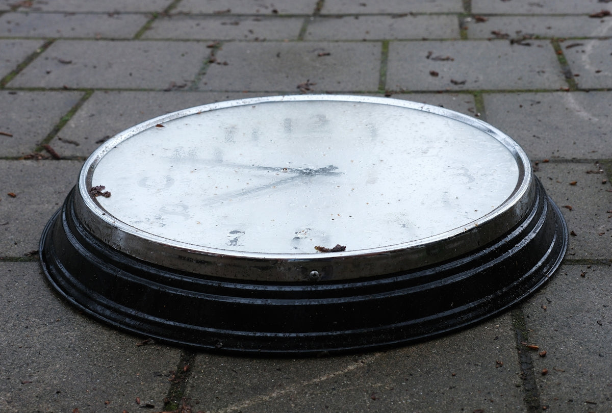 a black and white clock sitting on a sidewalk