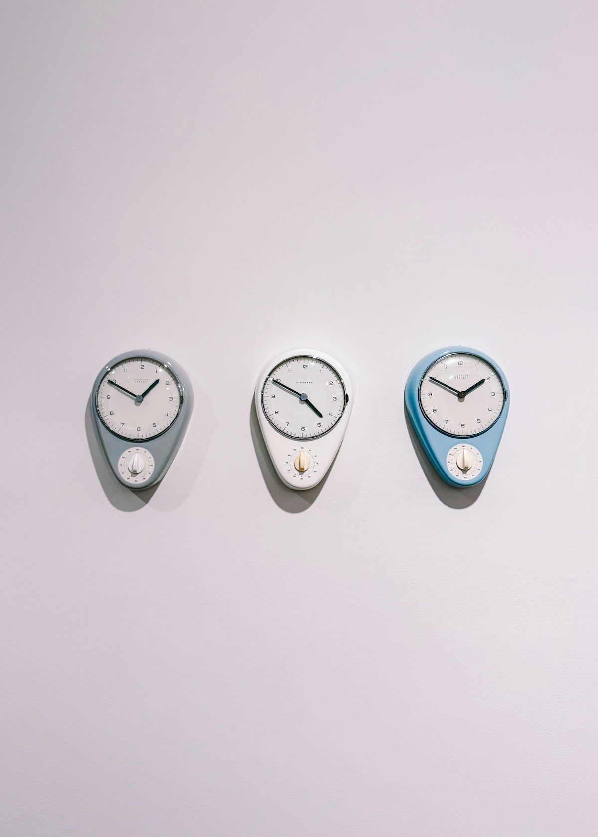 Three decorative clocks hanging on a white wall.