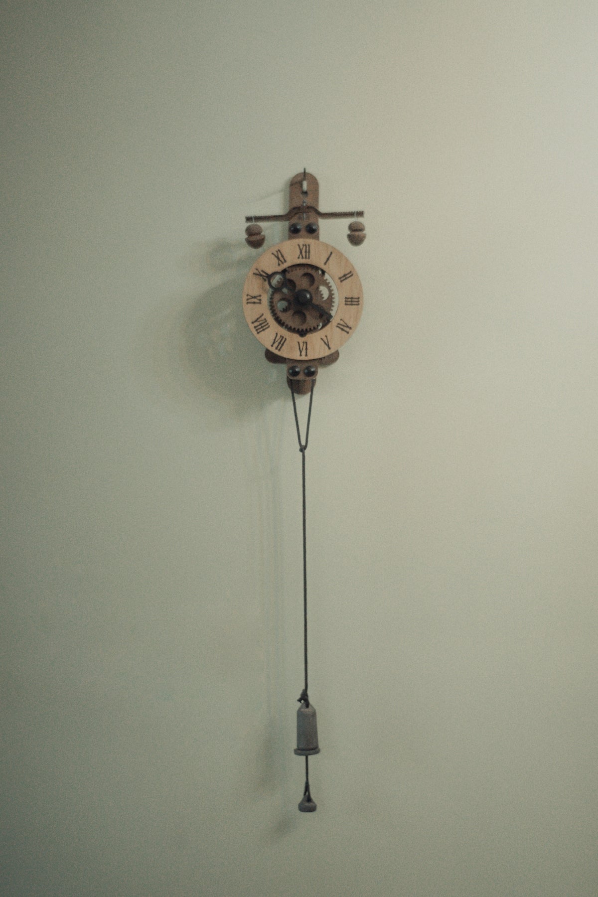 Antique pendulum clock hanging on a pale wall
