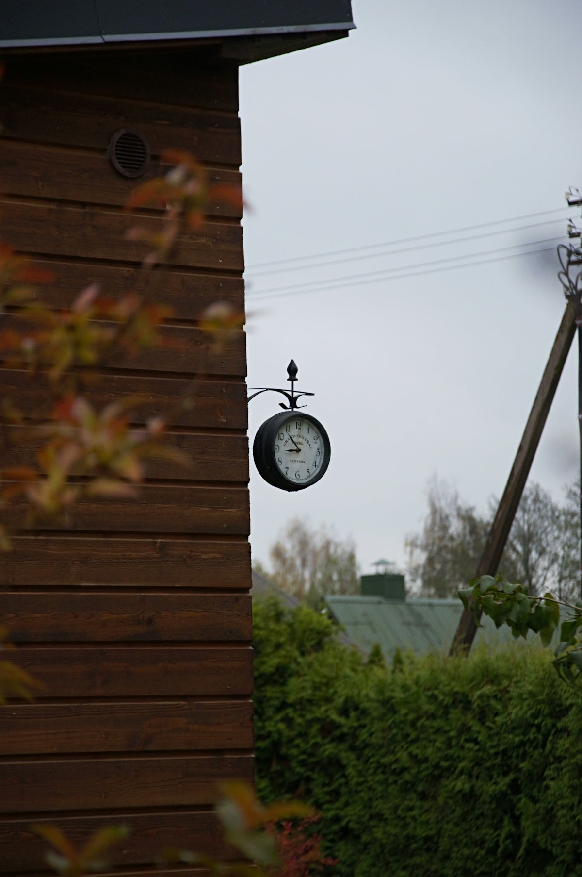Outdoor clock hanging on a wooden wall