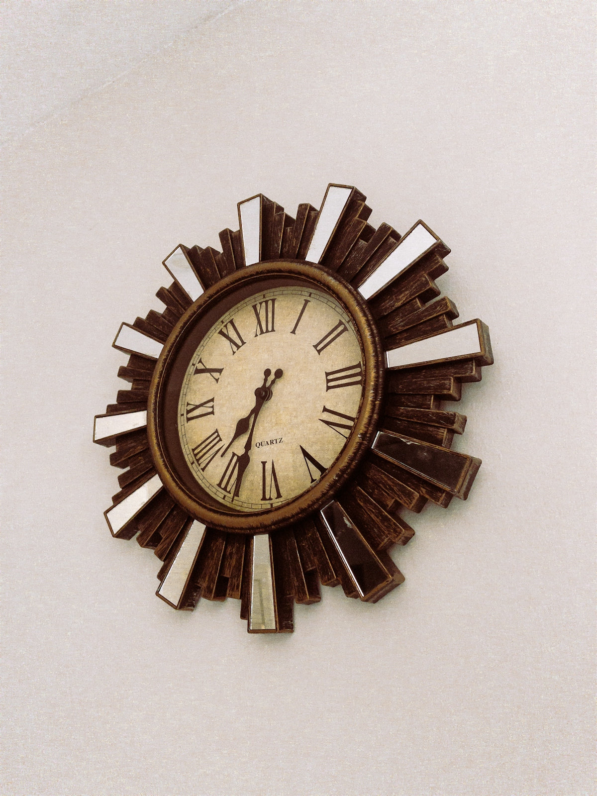 A decorative sunburst clock with roman numerals