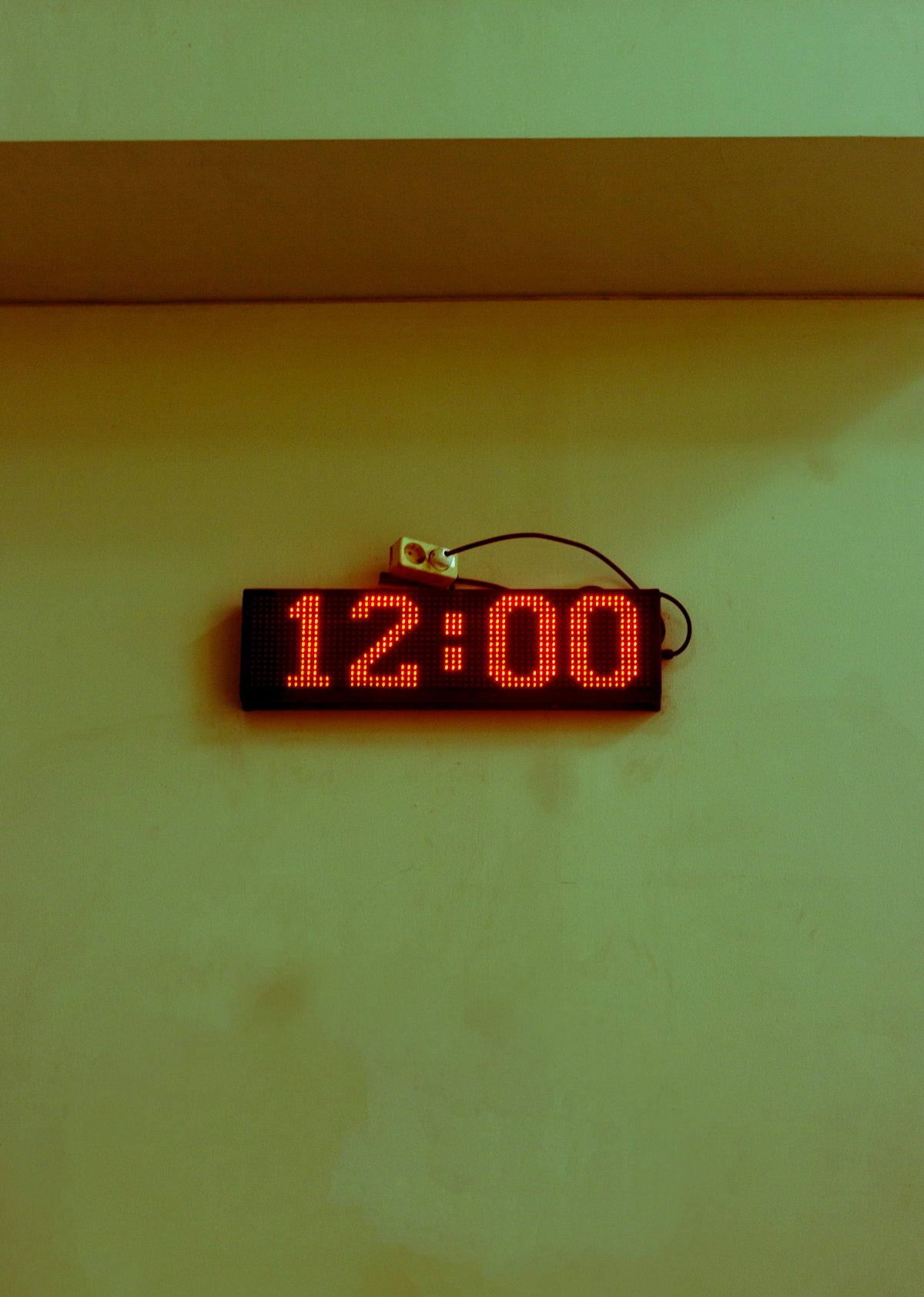 Digital clock displaying 12:00 on a wall